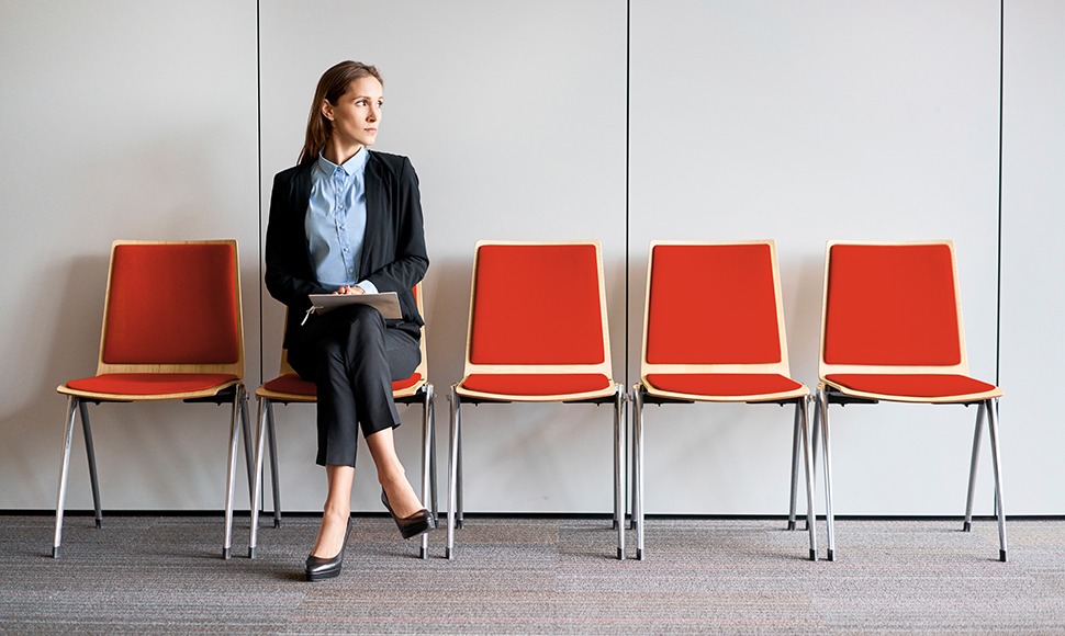 Woman sits in a row of chairs awaiting her job interview